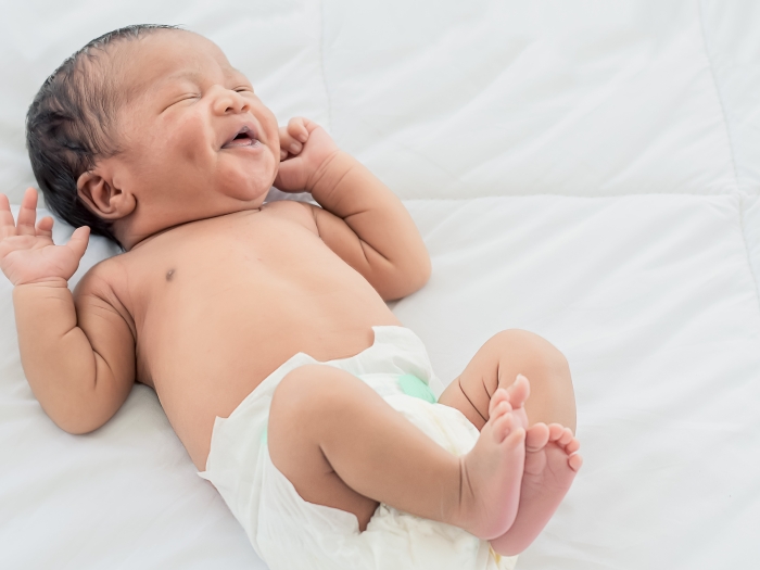 baby laughing on bed in diaper
