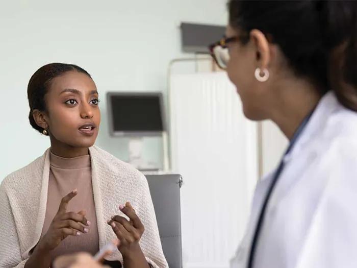 Black woman talks to her female doctor in an exam room