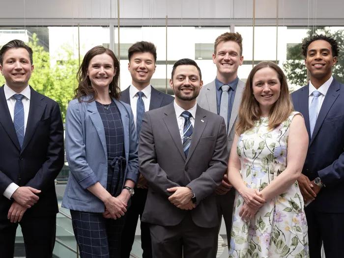 Ophthalmology residency class of 7 standing in front of a bank of windows.