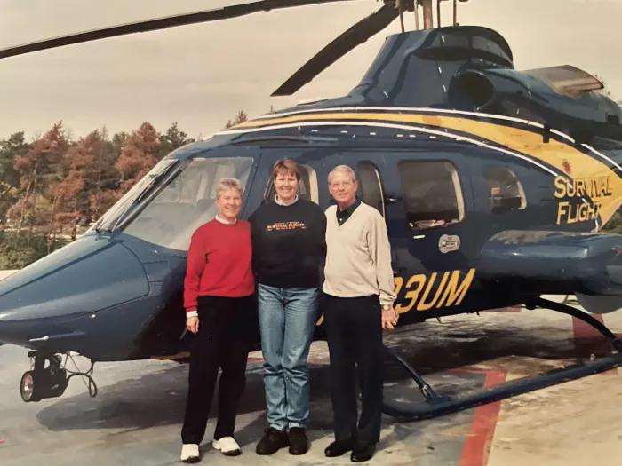 Sue, Elaine and Brian stand in front of a Survival Flight helicopter