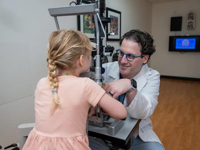 Adam Jacobson, M.D., uses ophthalmology equipment to examine the eyes of a pediatric patient.