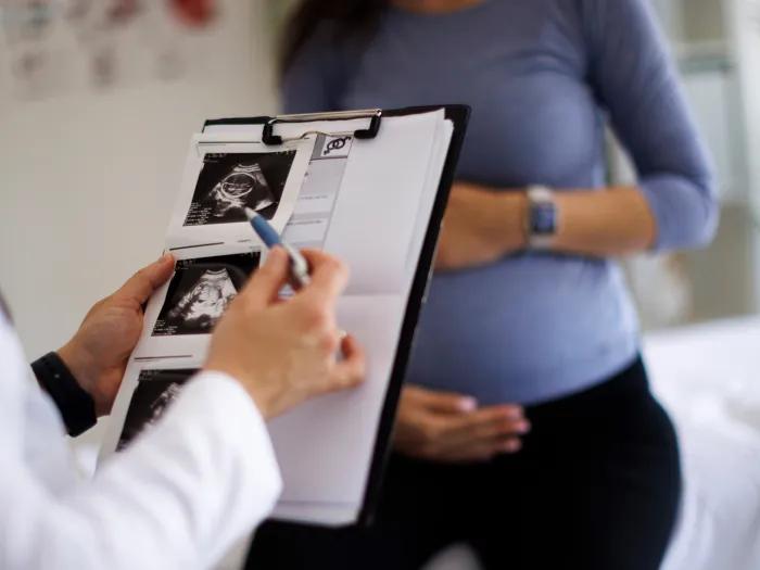 chart with sonogram images woman pregnant in background