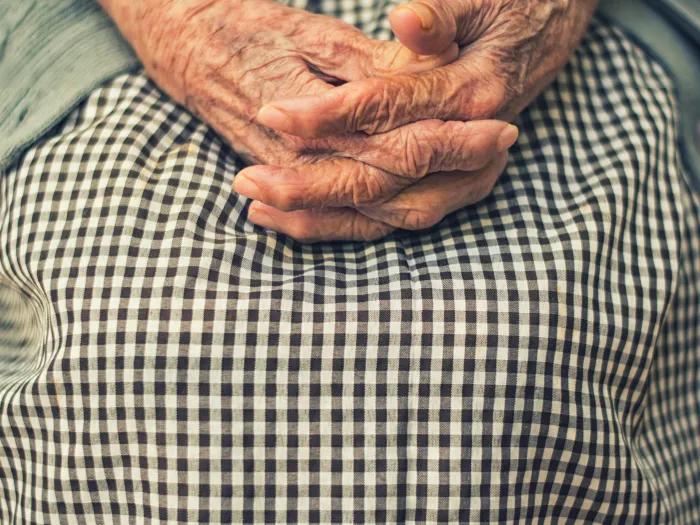 hands folded in the lap of an older individual