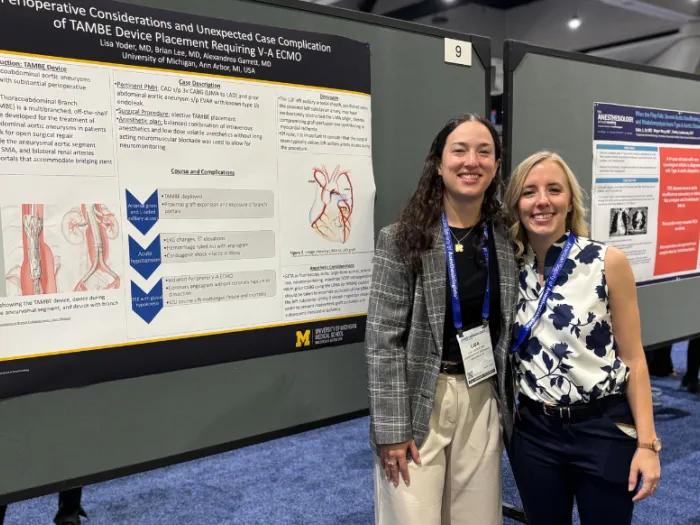 Two women pose next to a scientific poster at a conference poster session