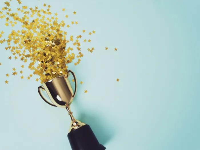 Gold trophy surrounded by a burst of gold stars against a light blue background.