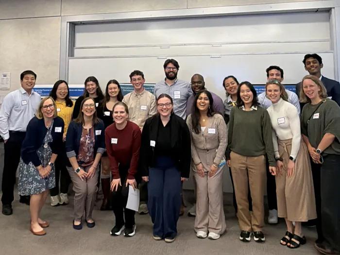 A group shot of student participants and faculty standing in two rows looking at the camera