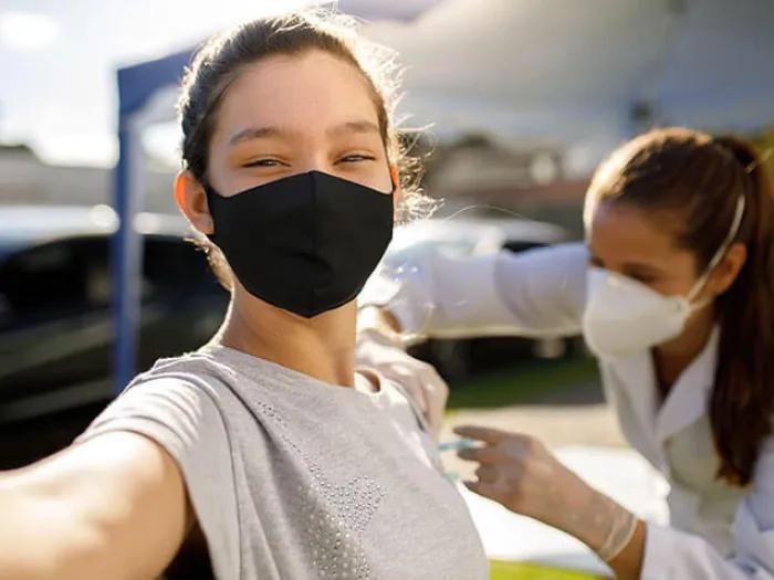 Teen taking a selfie with vaccination doctor mask on.