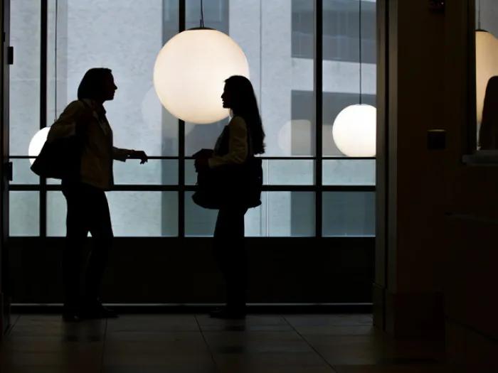 students talking in light silhouettes with light hanging behind shadow looking