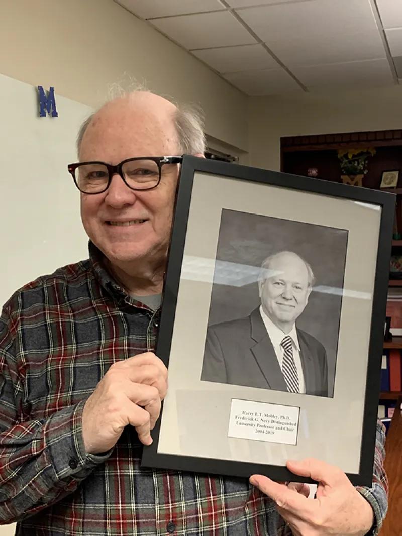 Professor Harry Mobley holds the photo of himself as M&I Chair