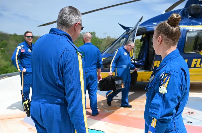 Members of survival flight prepare for takeoff as they stand around the helicopter and load things onto it.