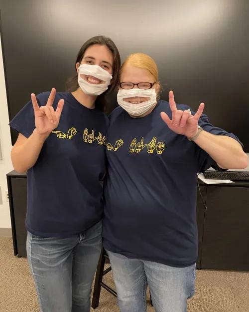 two women making ILY in sign language