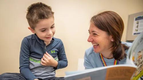 Woman and boy laughing while reading a book