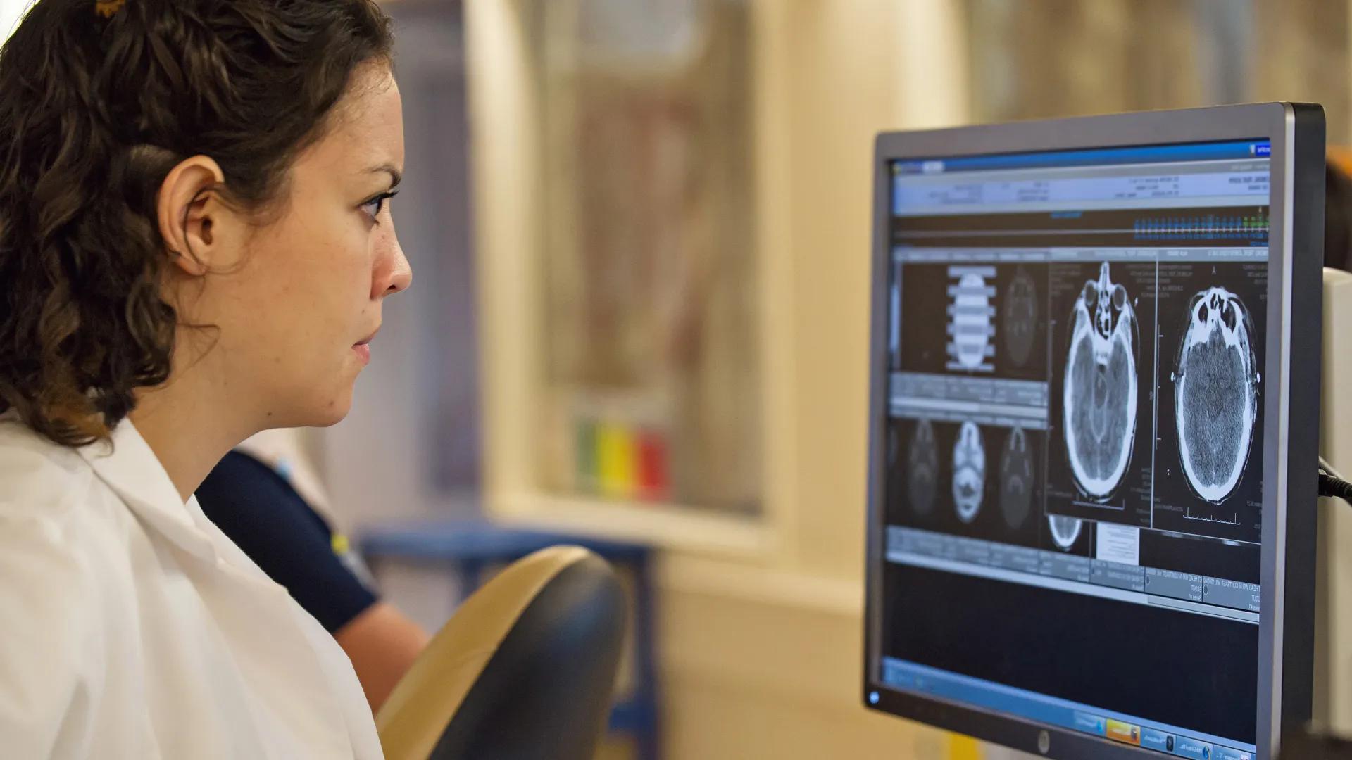 A woman in a lab coat looking at a computer screen.