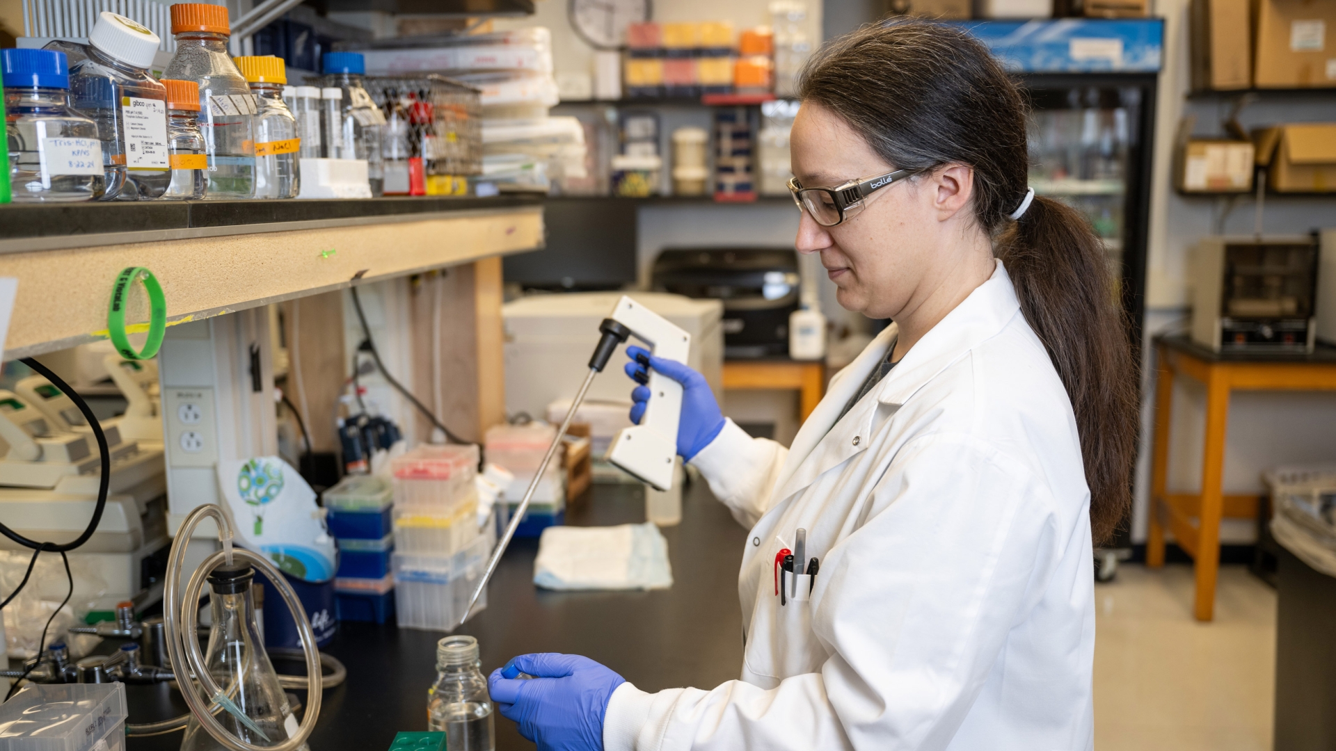  a faculty in a lab coat conducts an experiment, focused on her test in a laboratory setting.