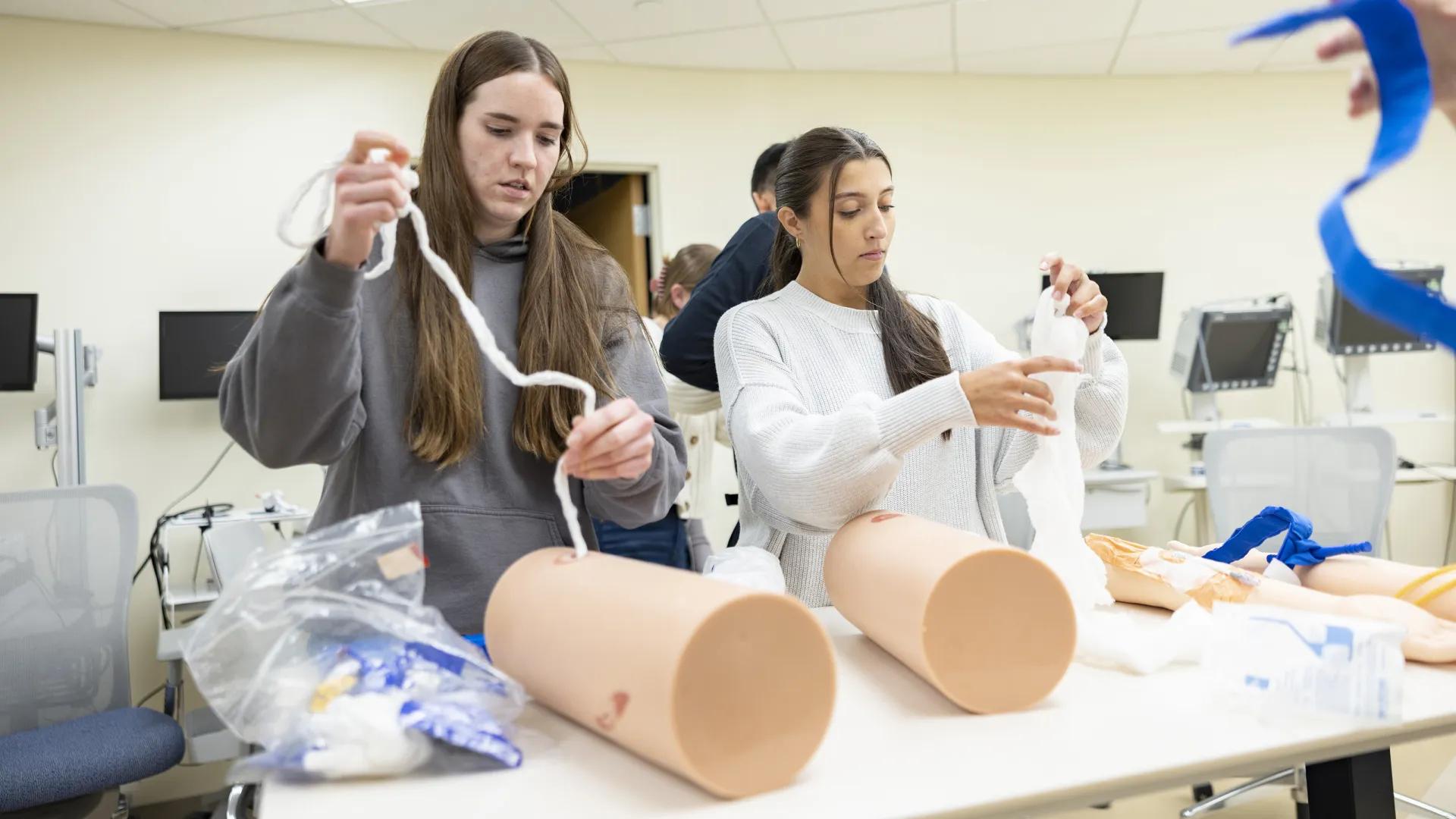 two medical students practice life saving skills in a simulated lab