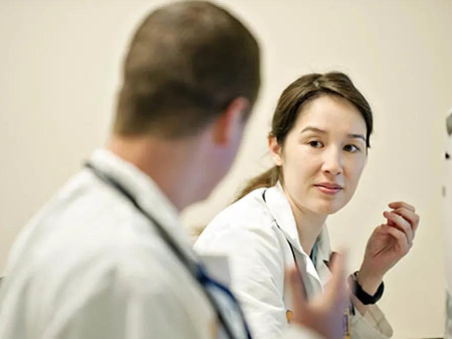 Female Asian physician in white coat wested with white male doctor with stethoscope