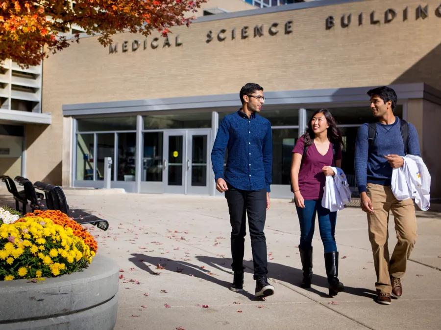 Three students walking across campus together