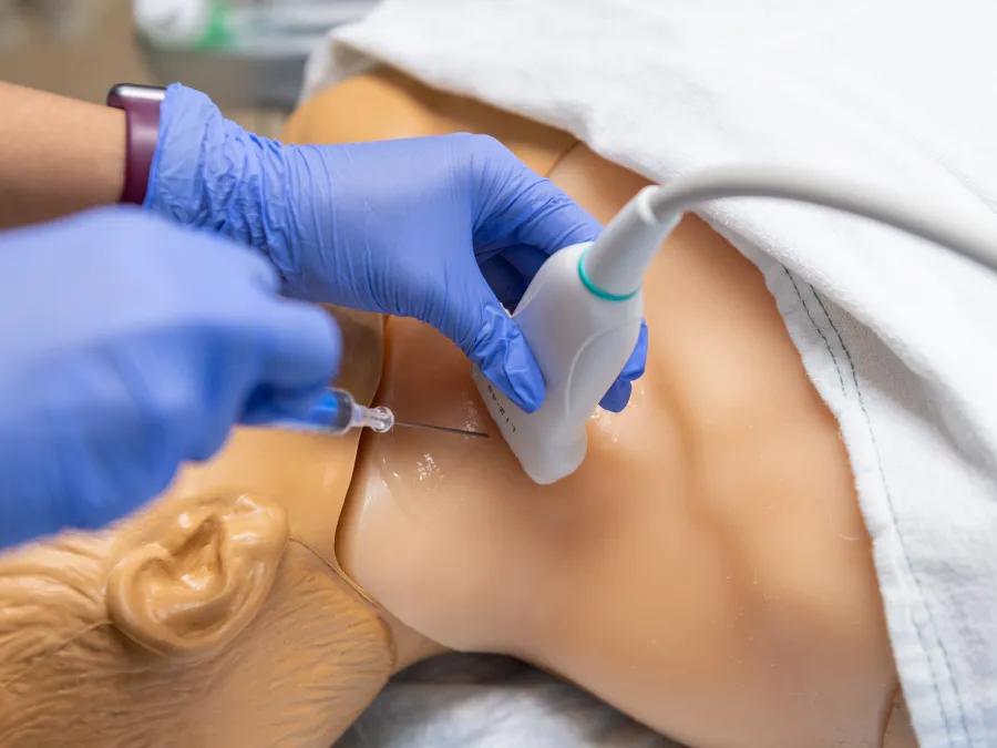 up close view of needle and hands holding ultrasound wand 