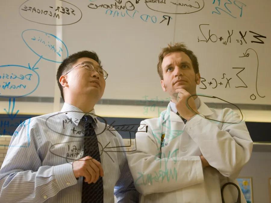 Two people looking at a whiteboard of written work