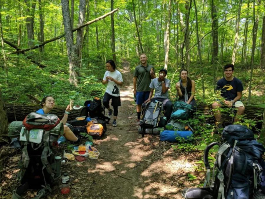 A group of students in the forest with camping gear