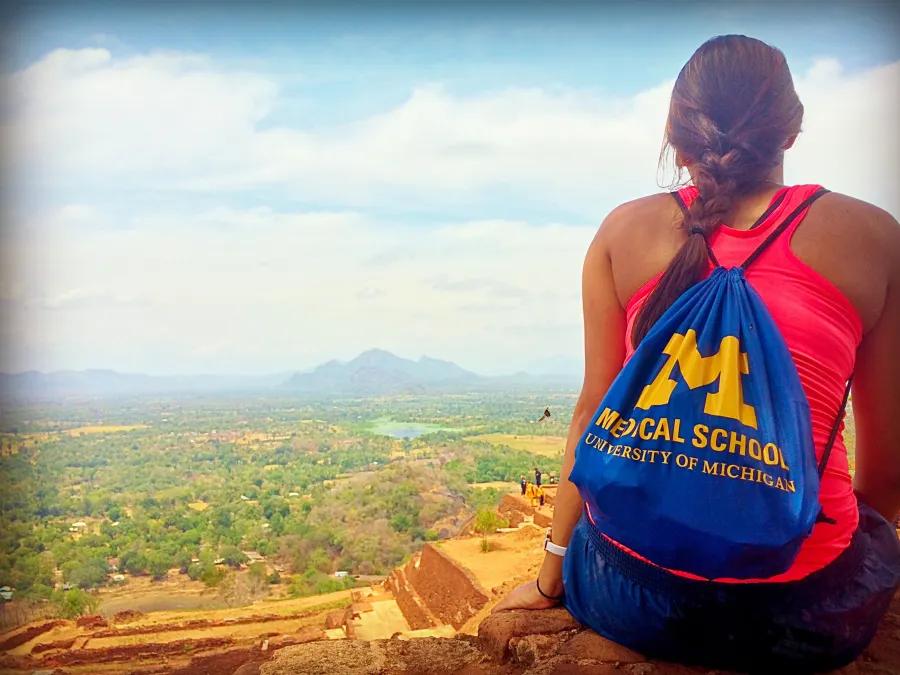 A girl sitting on a ledge looking at the view
