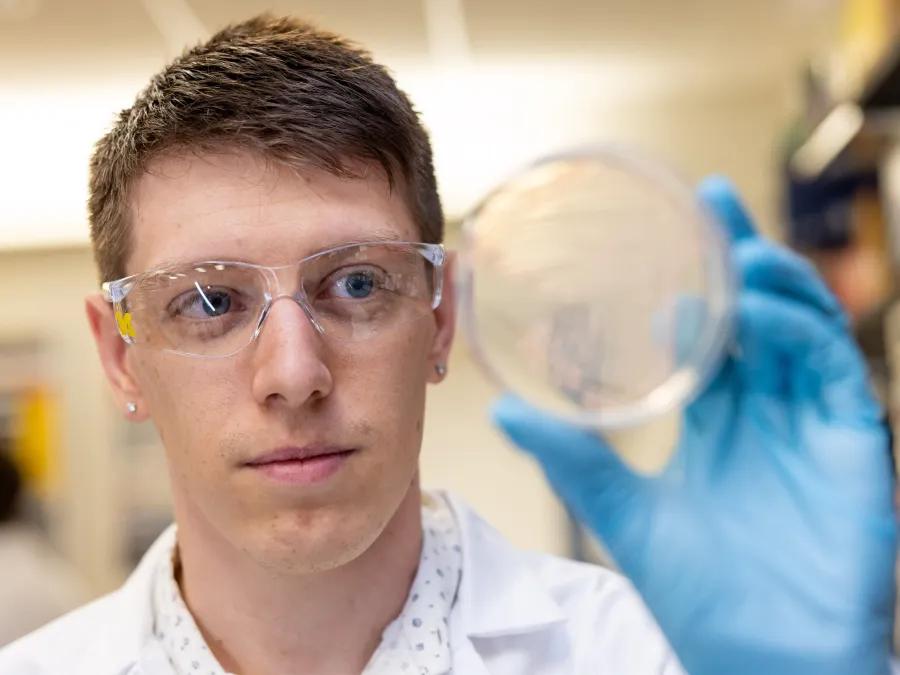 A close up shot of a man holding a petri dish