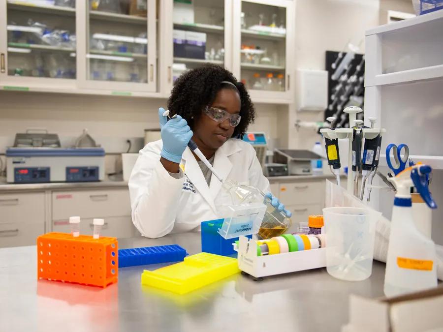 wide view of woman holding pipette in laboratory 