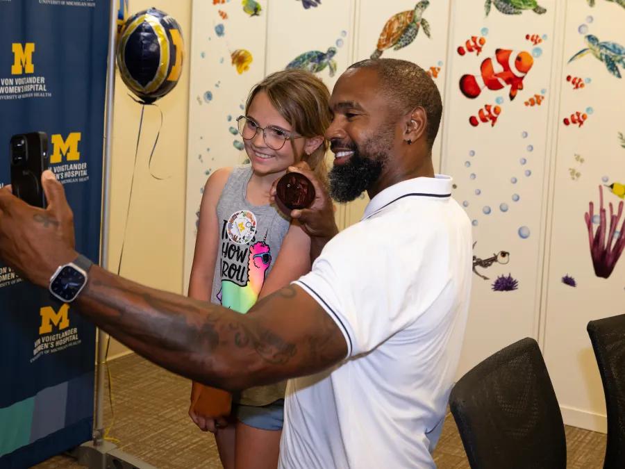 Charles Woodson and a young patient happily taking a selfie together.