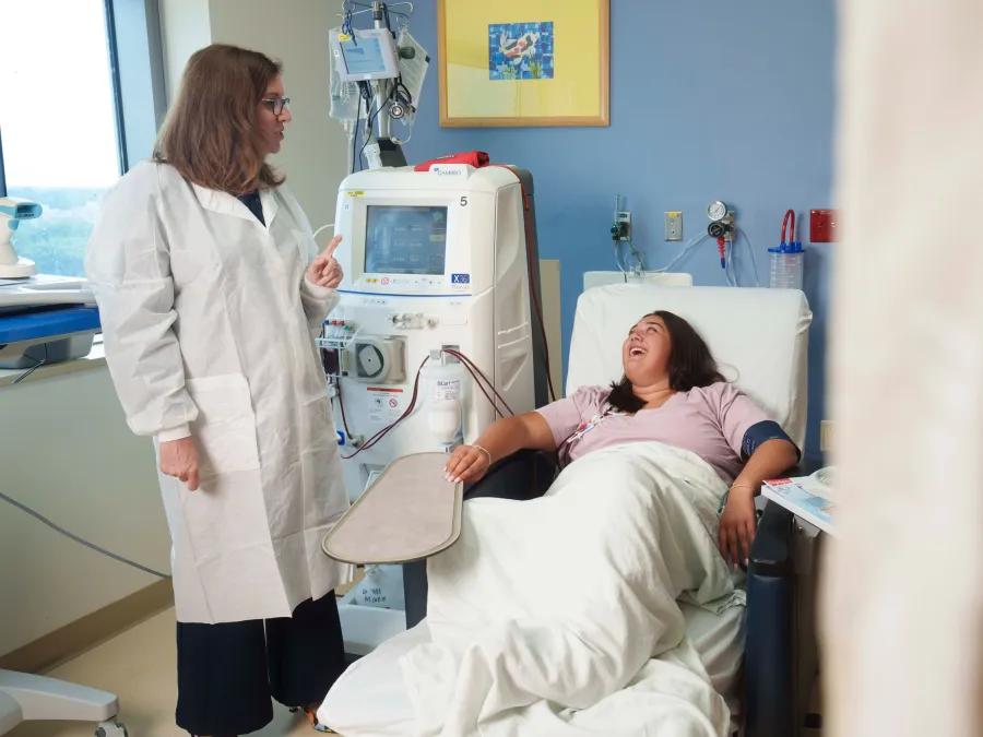 Physician conversing with patient on exam chair.