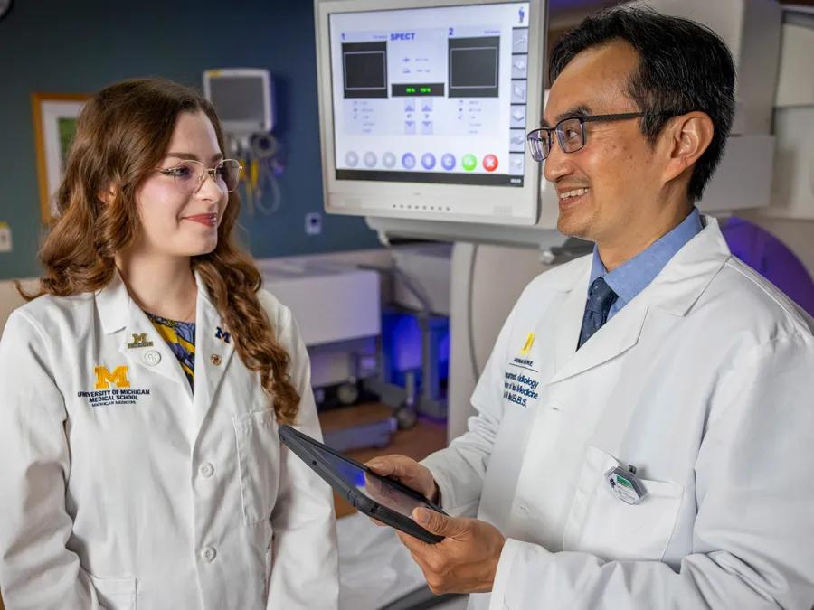 Doctor talks to med student while holding tablet