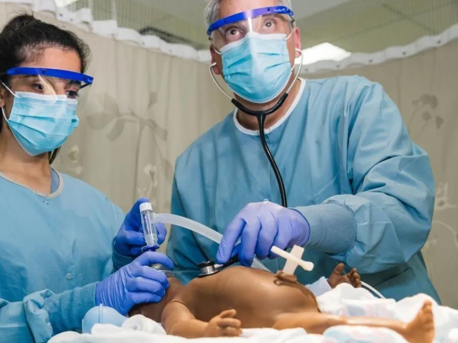 Two doctors perform resuscitation on baby.