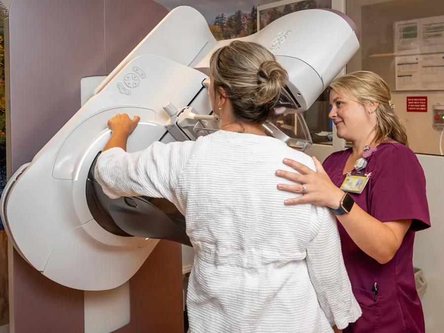 A technician assisting a patient with a breast imaging scan
