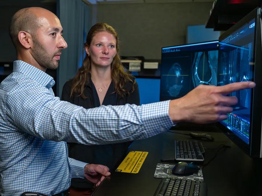 Two radiologists reviewing medical images on dual monitors