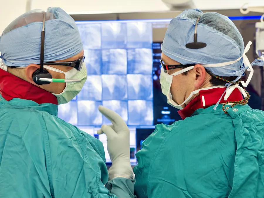 Two providers in scrubs discuss a scan in the OR