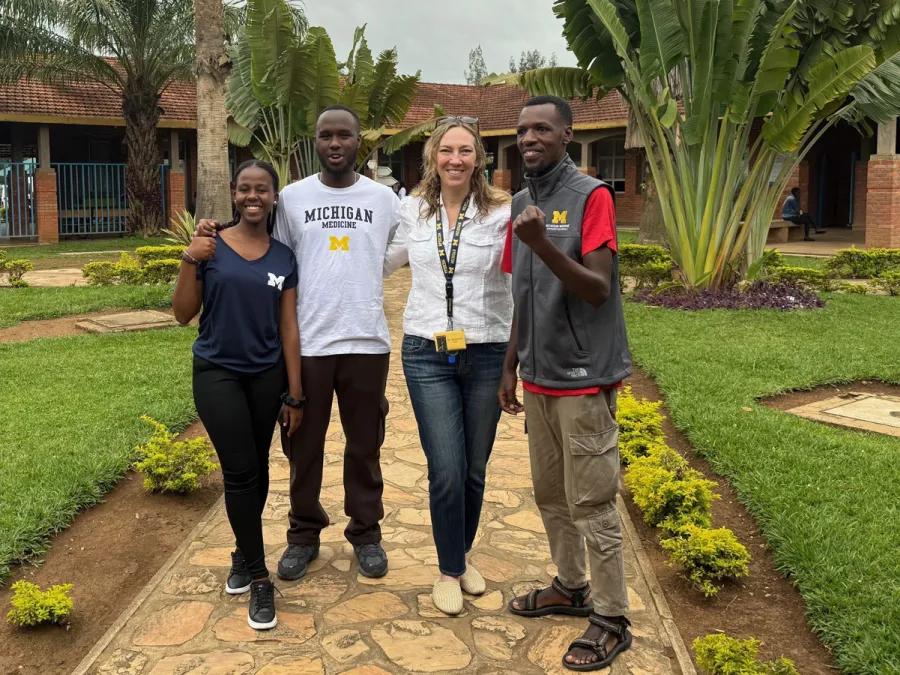 Trainees and clinician smile on a hospital campus walkway, highlighting global health exchange and collaboration