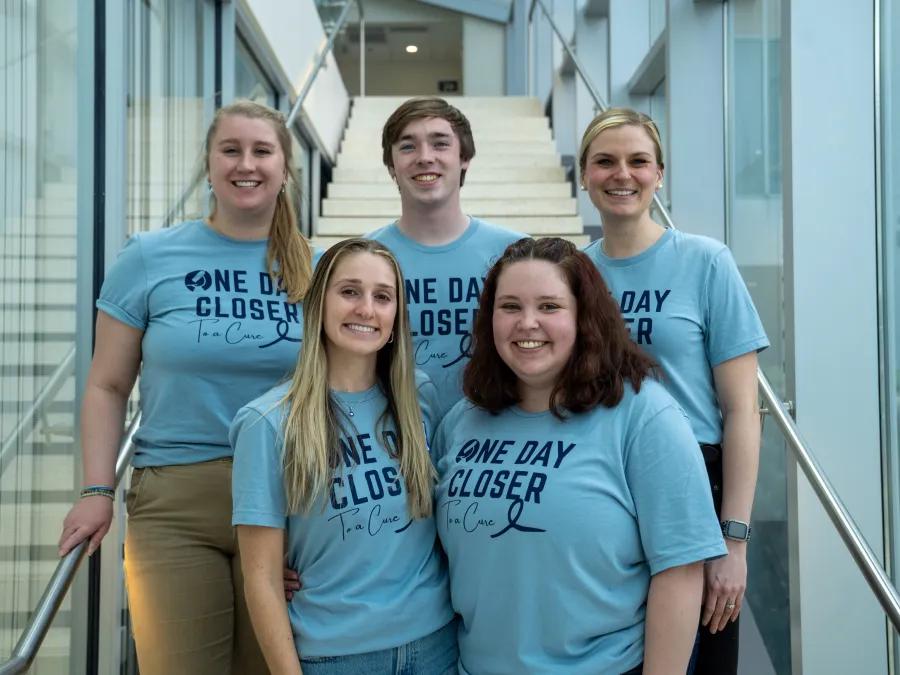 A group of students in blue shirts posing for a photo