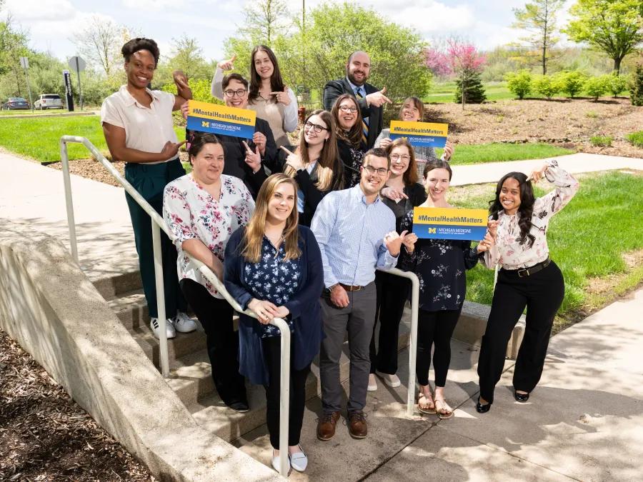 Current clinical neuropsych fellows stand outside together on a bright, spring day smiling and holding signs that say "mental health matters"