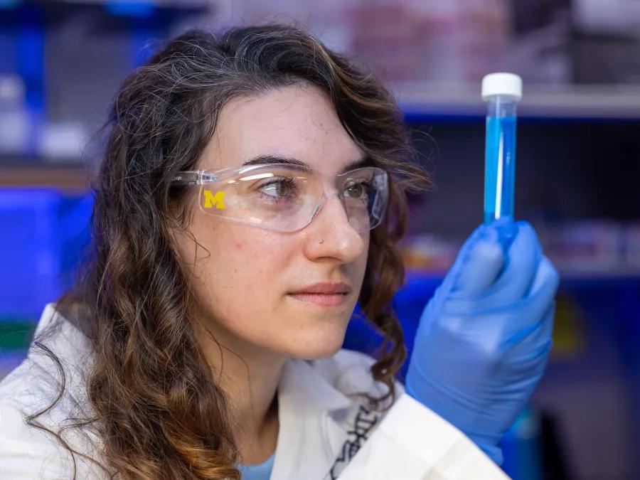 Lab member looking at a test tube in the lab