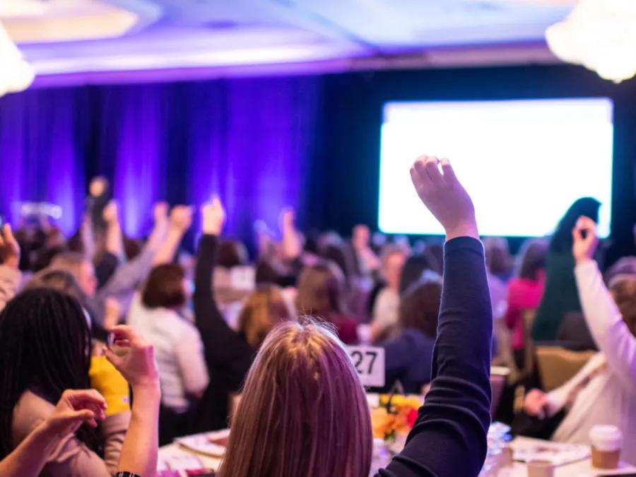 Attendees raising their hands at the Leadership Summit for Advancing Women in Academic Medicine & Healthcare