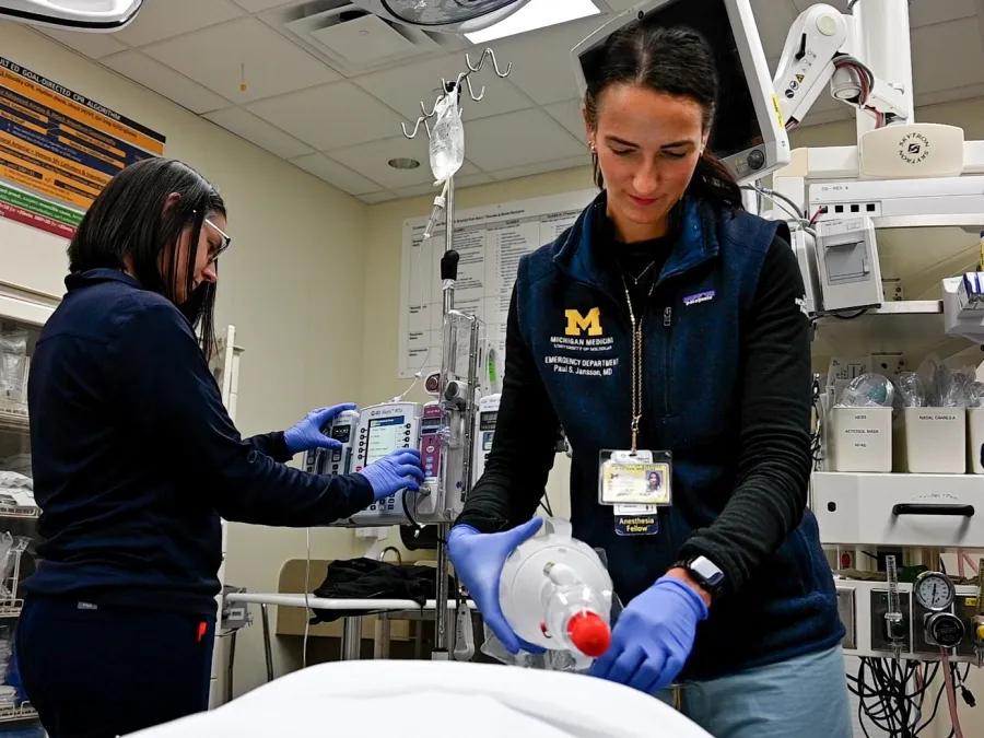 Two medical providers preparing equipment in an emergency department setting.