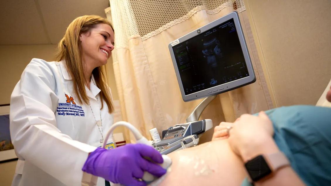  ultrasound technician moves scanner around on stomach