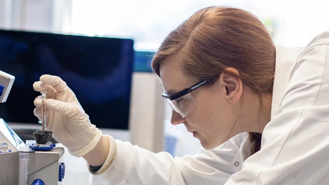 Lab student uses pipette to drop into tube 