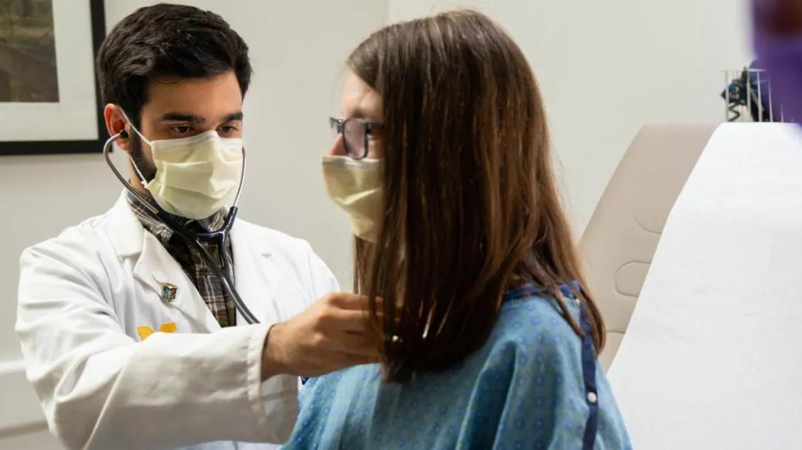 Patient in a doctor check up both wearing masks