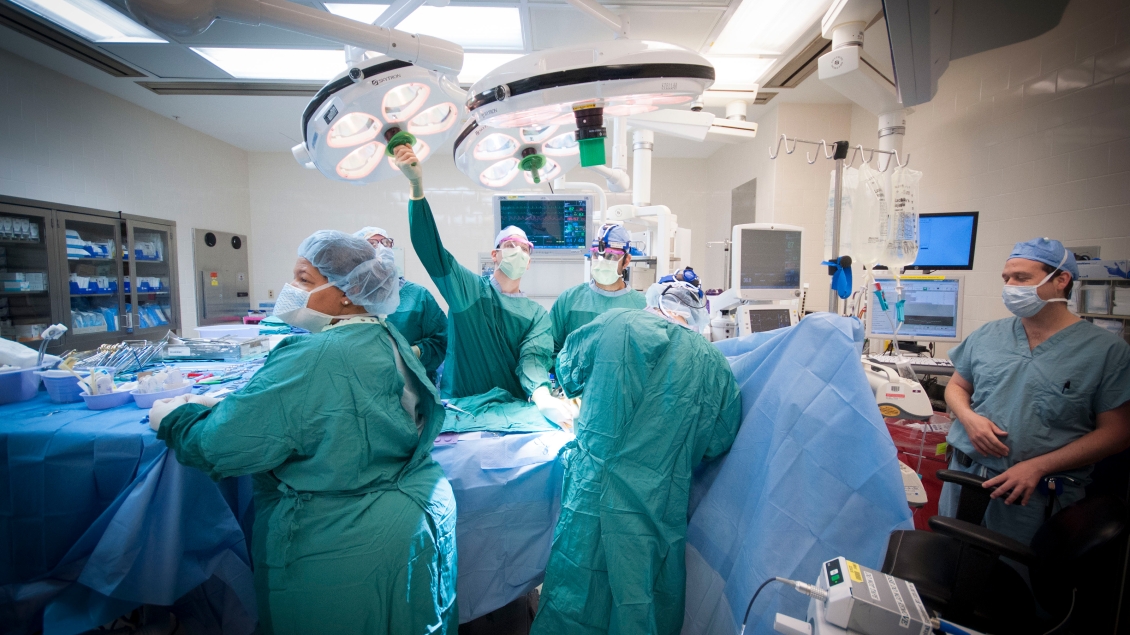 Doctors reaching for the overhead light in the operating room 