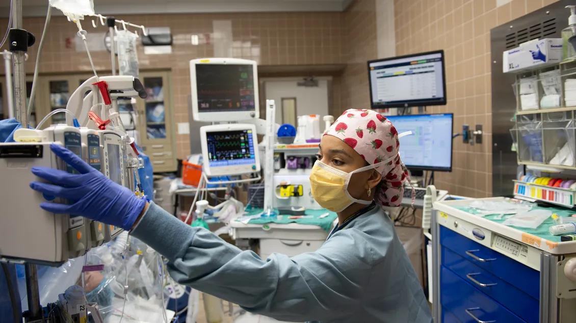 Nurse reaches over to check levels of the drip bags 