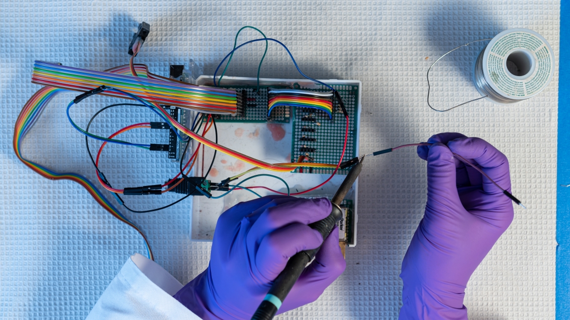 doctor in latex gloves works with wires in a part of a computer chip 