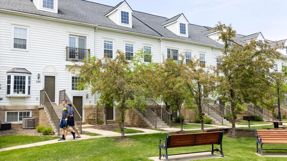 Two students walking past housing accomodations