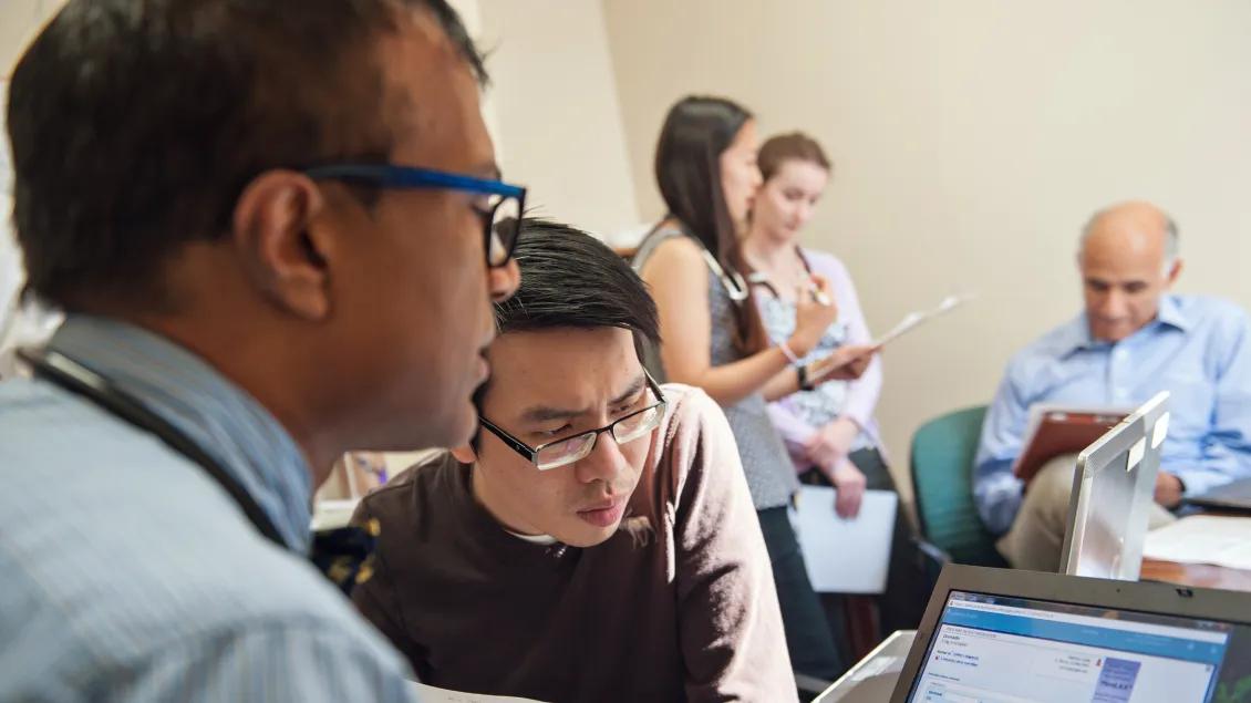 People in a room reviewing information on a laptop