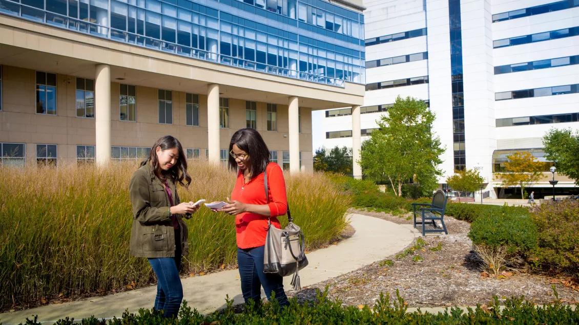Two people on phones outside a building