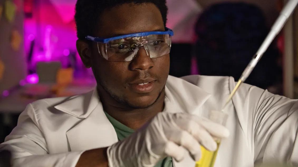 Man in goggles using a test tube